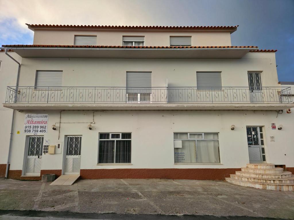 Un edificio blanco con un balcón en la parte superior. en Alojamentos Altamira, 
