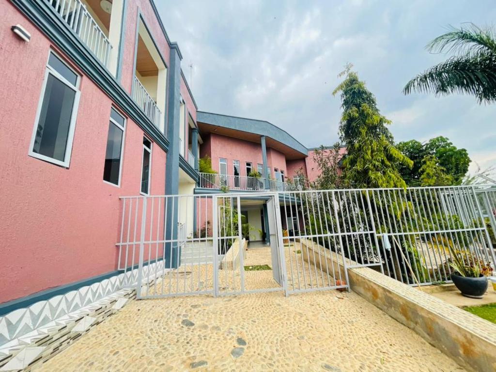 een roze gebouw met een hek ervoor bij Muraho Apartment in Kigali