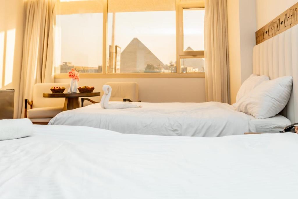 Dos camas en una habitación de hotel con ventana. en Superior Pyramids View, en El Cairo