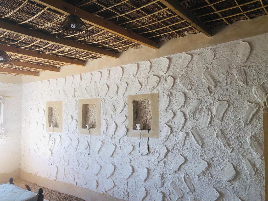 a white wall with three pictures on it at Esewan siwa oasis in Siwa