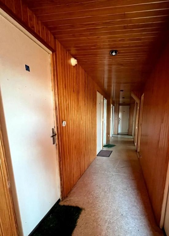 un pasillo con paredes de madera y un largo pasillo con puertas en Hôtel de Bruay la buissiere, en Bruay-la-Buissiere