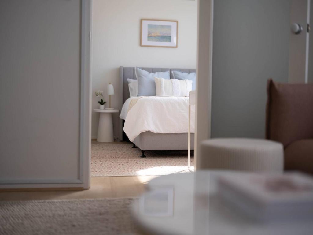 a bedroom with a white bed and a chair at Villa Amari - A Sunny Tranquil Home in Melbourne