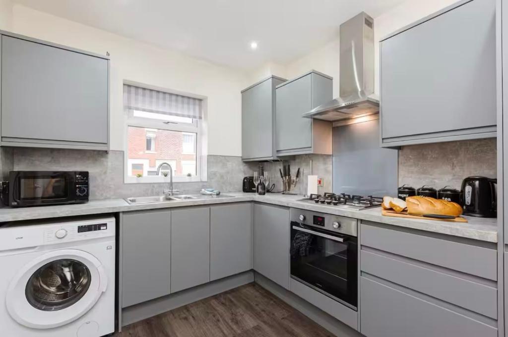 eine Küche mit weißen Schränken und einer Waschmaschine und einem Trockner in der Unterkunft Norris Stays - Sleeps 7 by M55 in Preston