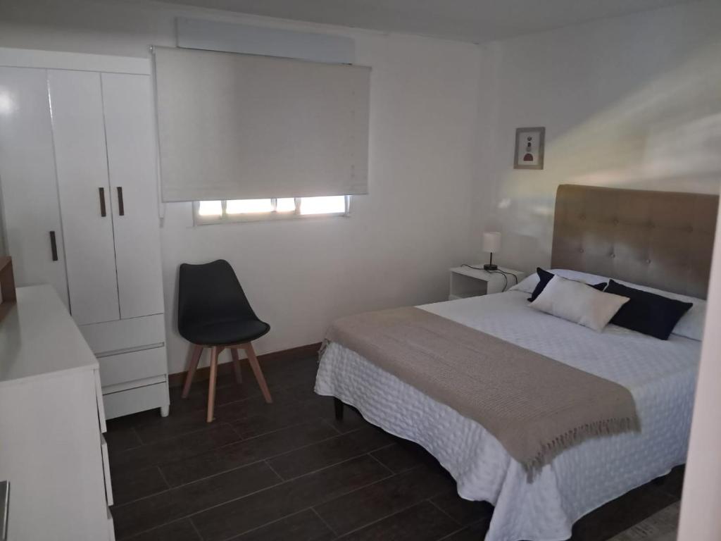 een slaapkamer met een bed, een stoel en een raam bij Casa bella in Durazno