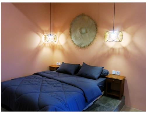 a bedroom with a blue bed and two lights at apartement Puri 2 in Jimbaran