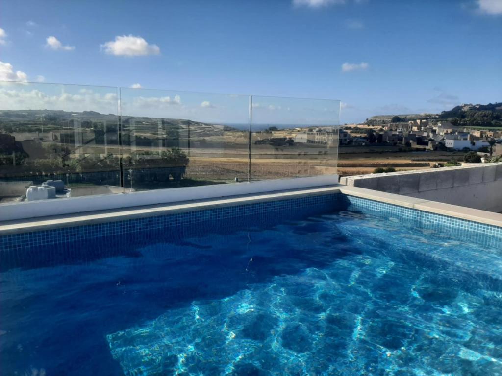 een zwembad met uitzicht op de oceaan bij Sunsets Duplex Penthouse Gozo in Kerċem