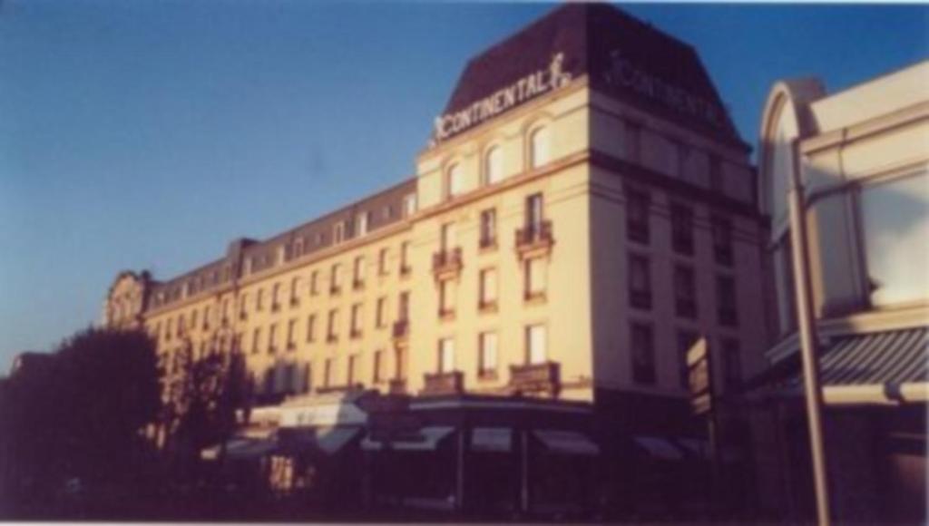 Un grand bâtiment blanc avec un panneau en haut dans l'établissement Residence Le Continental, à Vittel