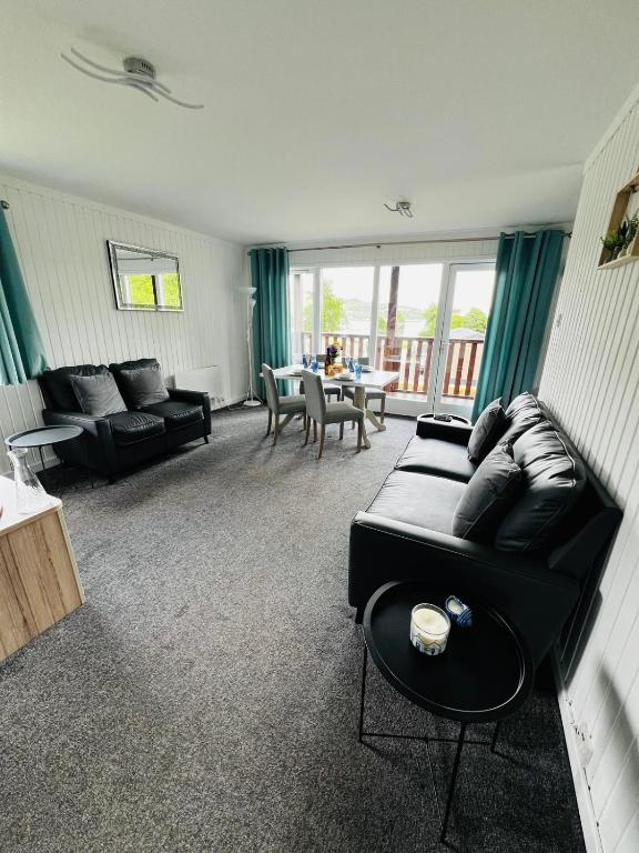 a living room with a black couch and a table at Tigh Na Sealladh in Dunoon