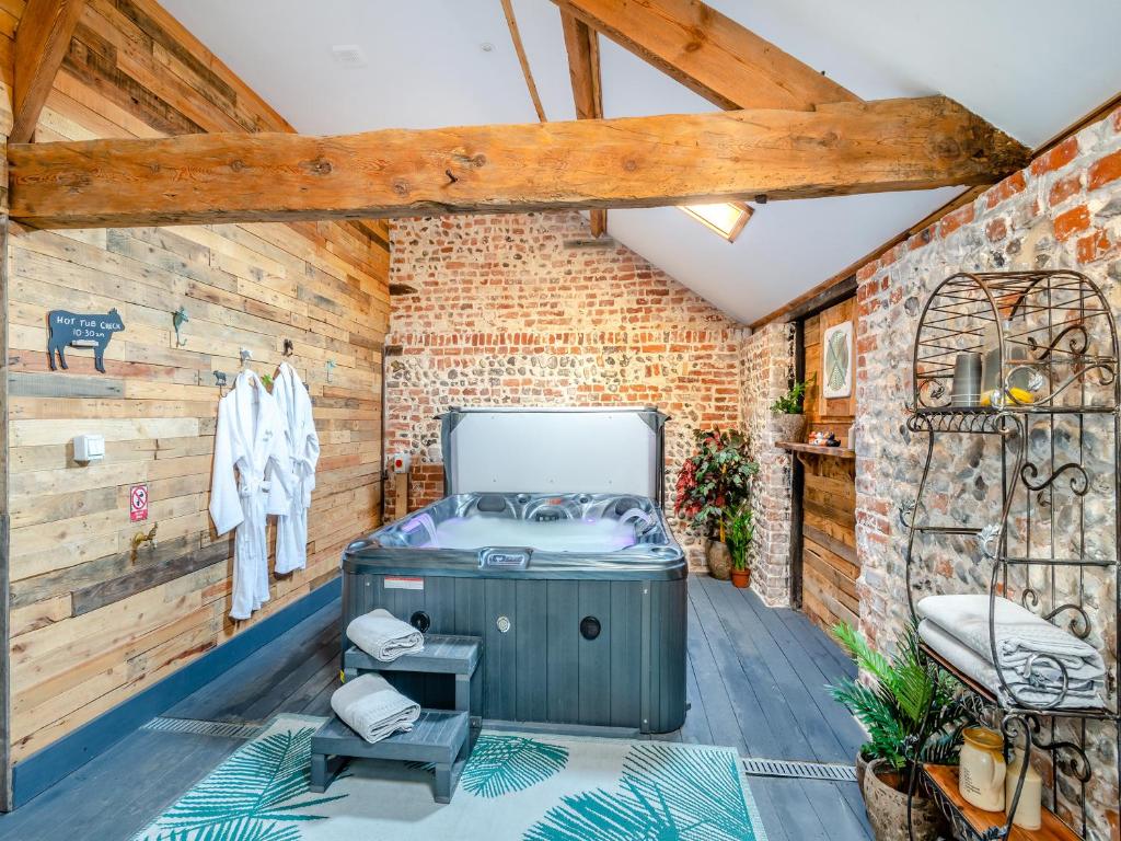 a room with a hot tub in a brick wall at Bockety Barn in Stalham