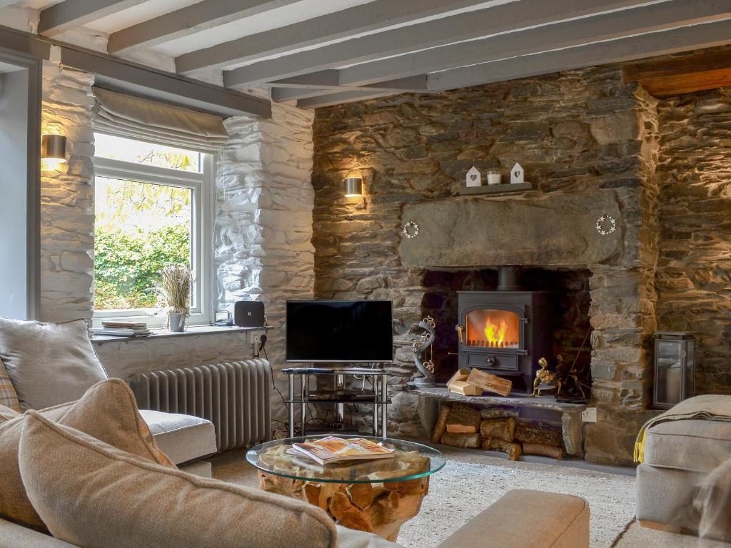a living room with a stone wall with a fireplace at Grange End Coach House in Grasmere