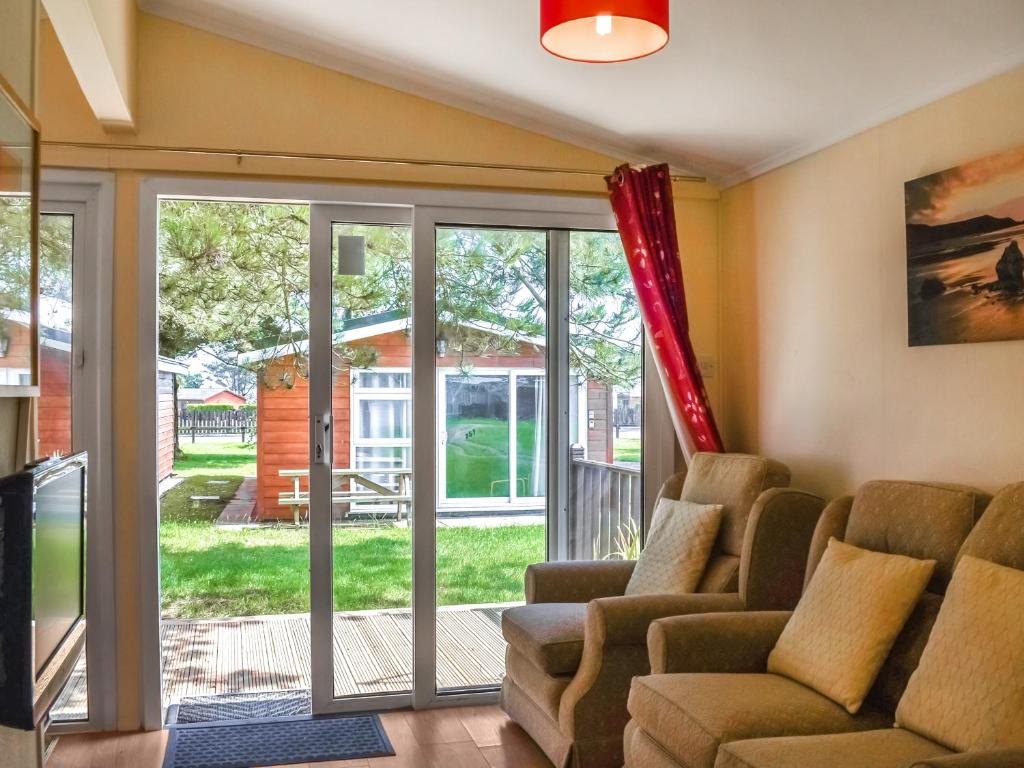 ein Wohnzimmer mit einer Couch und einer Glasschiebetür in der Unterkunft Harbour Cove - Uk47722 in Saint Merryn