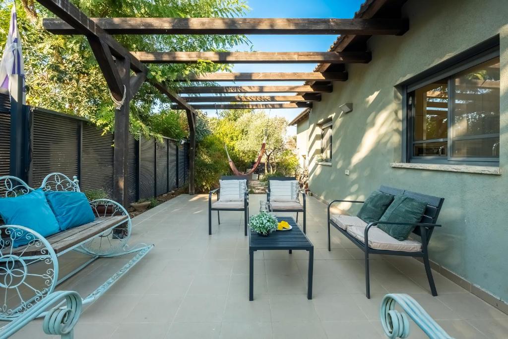 a patio with chairs and a table and a pergola at Sunny Hilltop Hideaway by Sea N' Rent in Tefahot