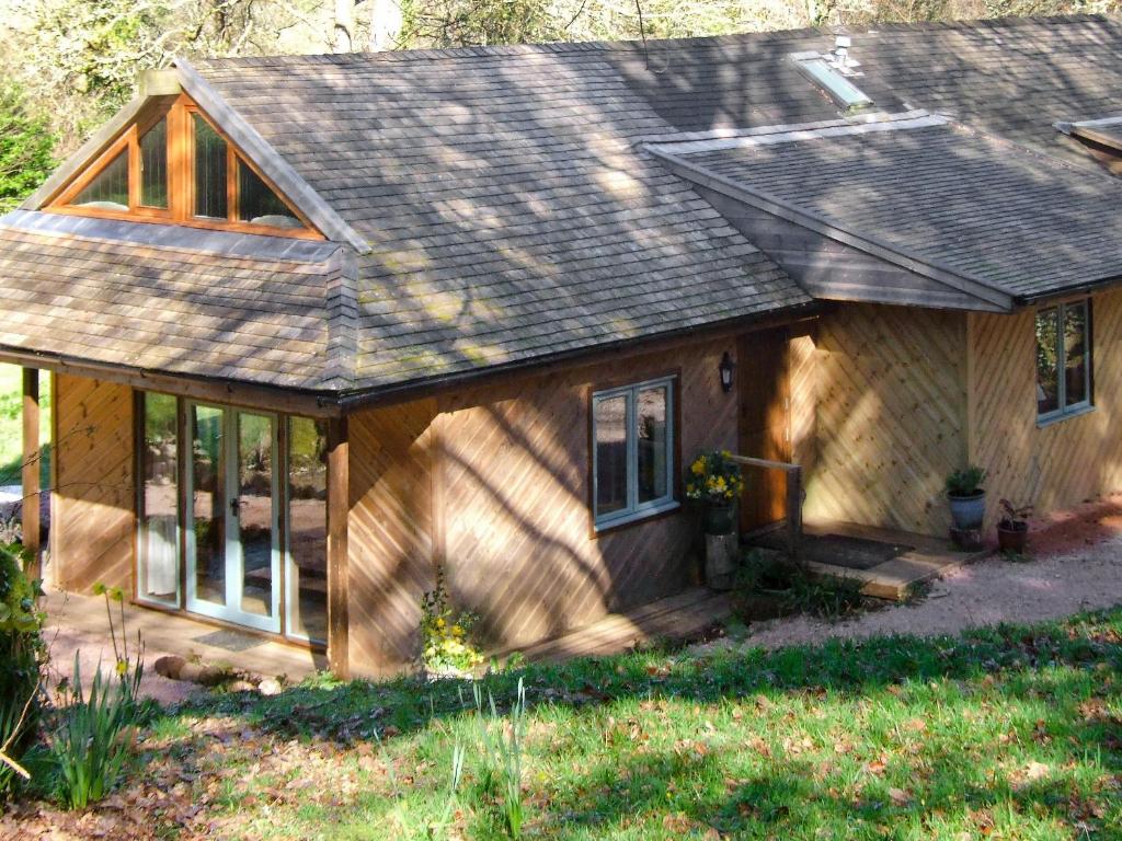 een klein houten huis met een veranda en ramen bij Brook Lodge in Bridford