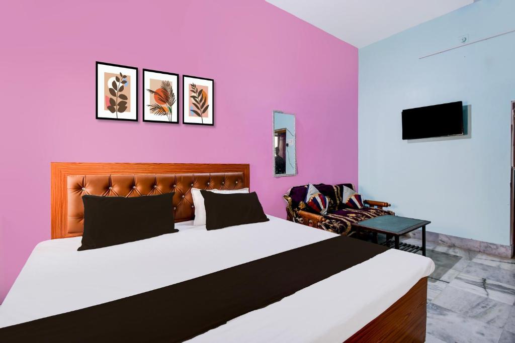 a bedroom with a large bed and a pink wall at Hotel O Magadh Guest House in Gaya