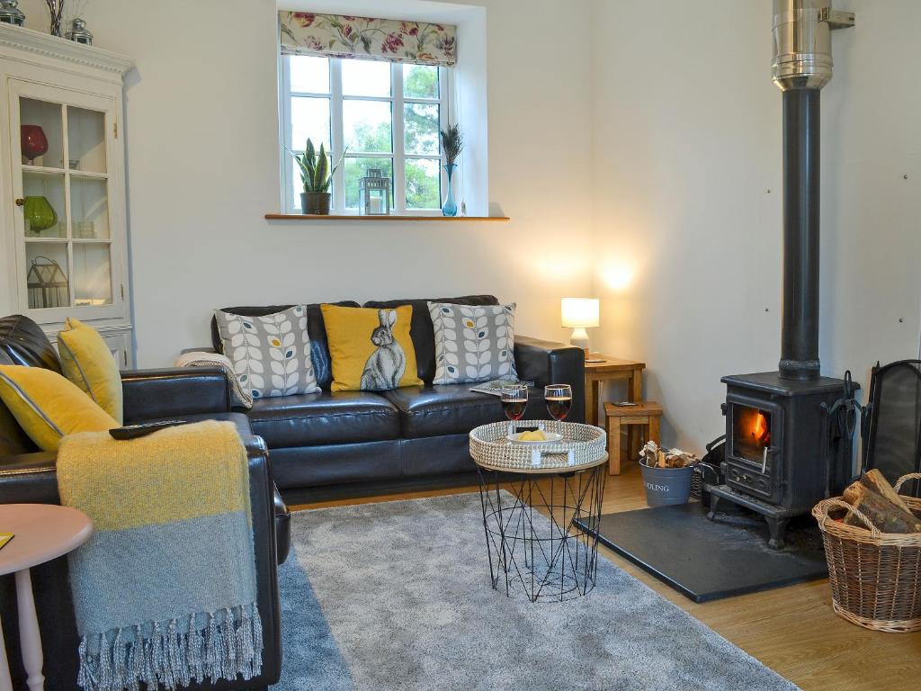 AshwaterにあるMeadowside Forgeのリビングルーム(黒い革張りのソファ、薪ストーブ付)