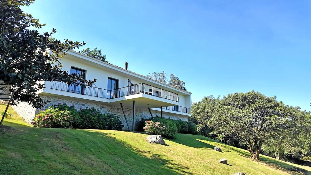 a large white house on a hill with trees at Villa Vacacional Las Encinas in Cuerres