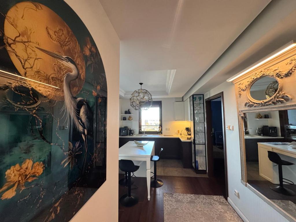 a living room and a kitchen with a painting of a bird at Apartament Transatlantyk in Gdynia
