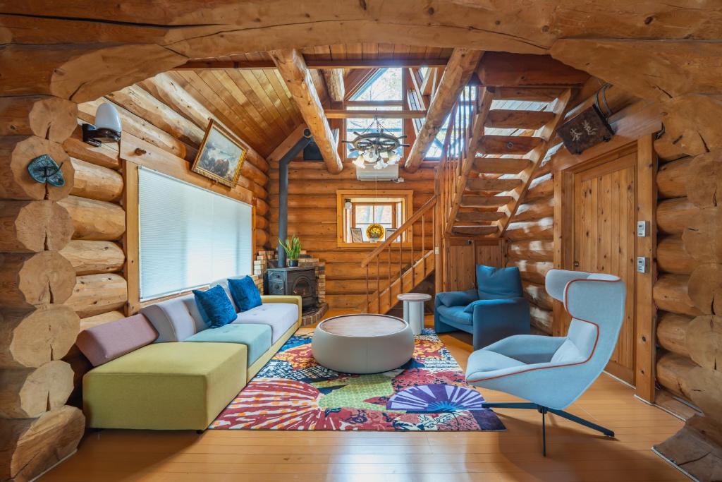 a living room with a couch and chairs in a log cabin at Hakuba Riverside Loghouse in Hakuba