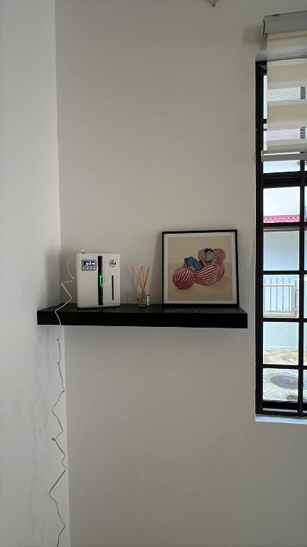 a shelf on a wall with a picture and a window at B&C Homestay in Miri