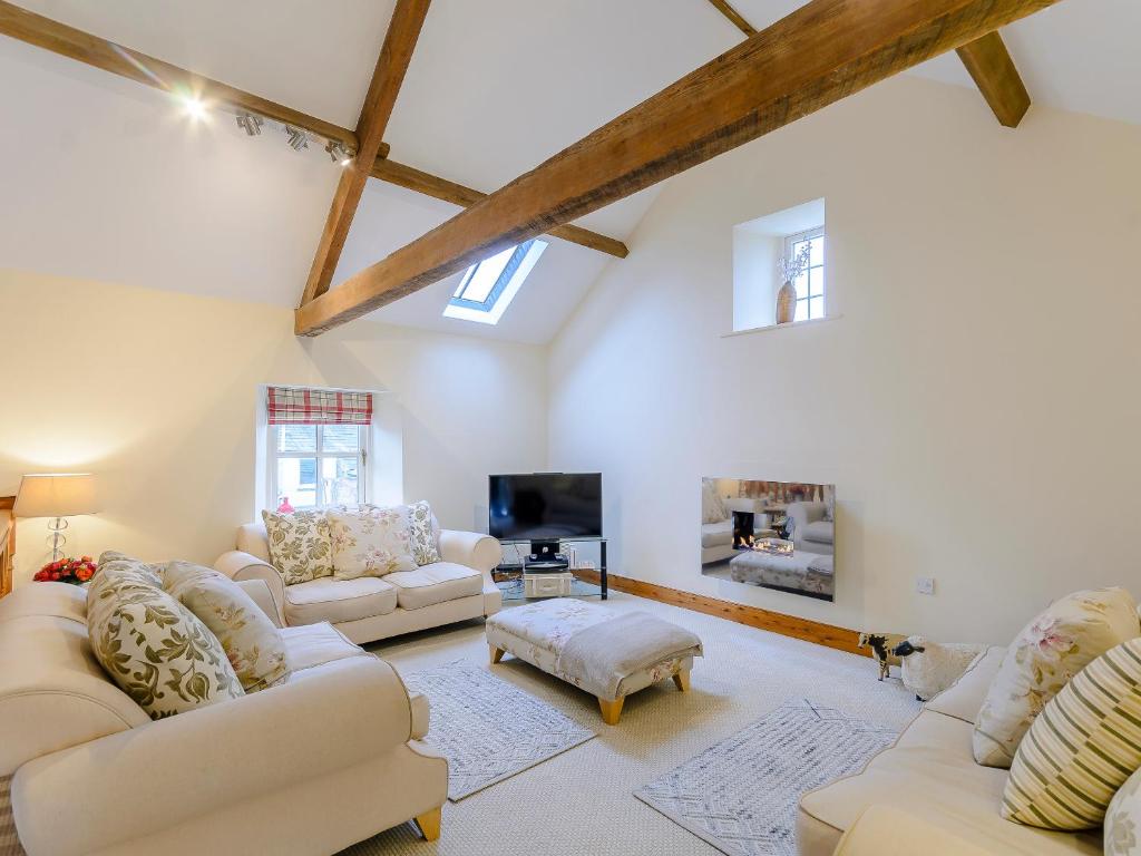 a living room with white furniture and a tv at Westwood Barn in Brough Sowerby