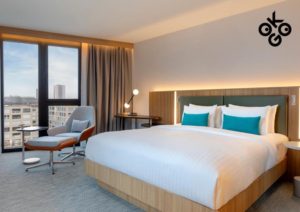 比尔Courtyard by Marriott Biel Bienne的配有一张大床和一把椅子的酒店房间