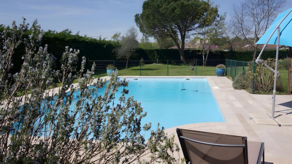 une piscine avec deux chaises et un parasol dans l'établissement Gîte Avec Piscine La Petite Gironde, à Porchères