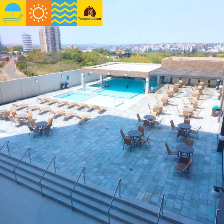 a patio with tables and chairs next to a pool at Piazza diRoma com acesso ao Acqua Park - CAROL Temporada CN in Caldas Novas