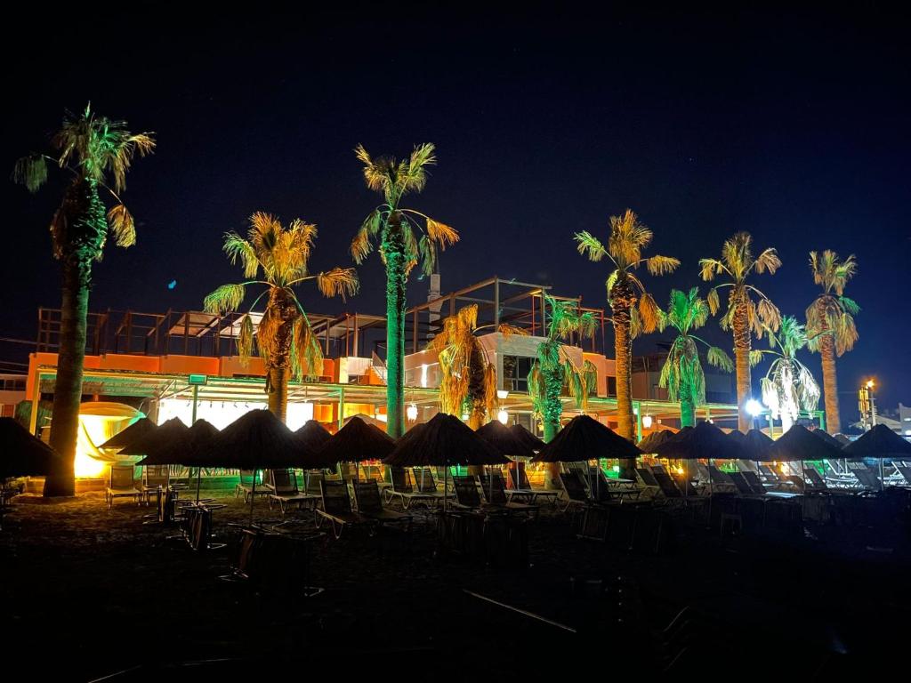 a resort with palm trees and umbrellas at night at Grand Cennet Beach Hotel in Akcay