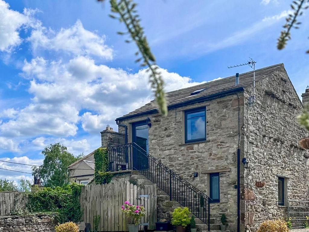 a stone house with a balcony and a fence at The Owlery At Aysgarth in Aysgarth