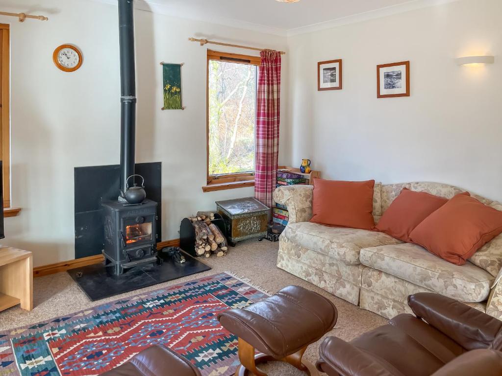 ein Wohnzimmer mit einem Sofa und einem Holzofen in der Unterkunft Nether Carness in North Ballachulish