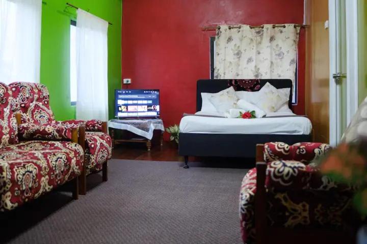 a bedroom with a bed and a couch and a chair at sunny's homestay in Singatoka