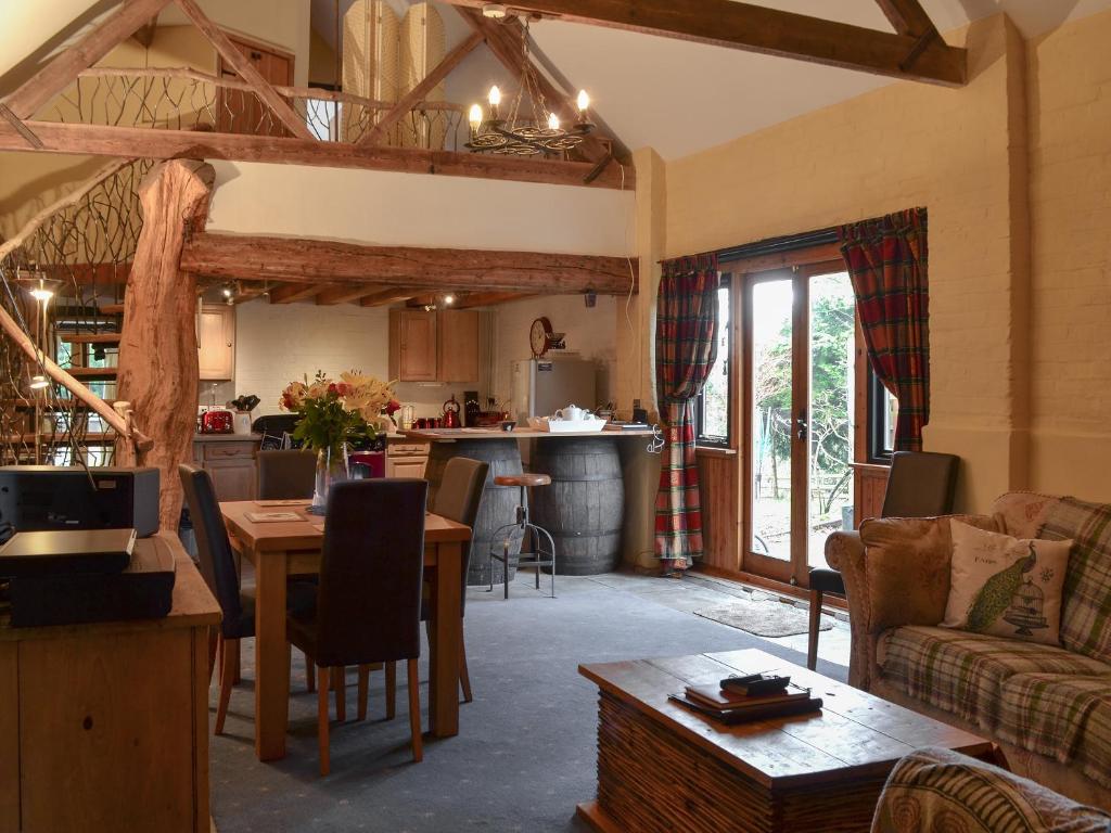 een woonkamer met een tafel en een keuken bij Meadow Barn in Ellingham