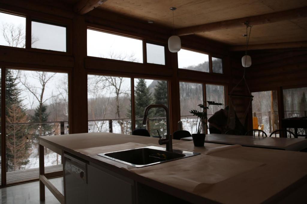 a kitchen with a sink and some windows at Hébergement Mauricie, La Tuque in La Tuque
