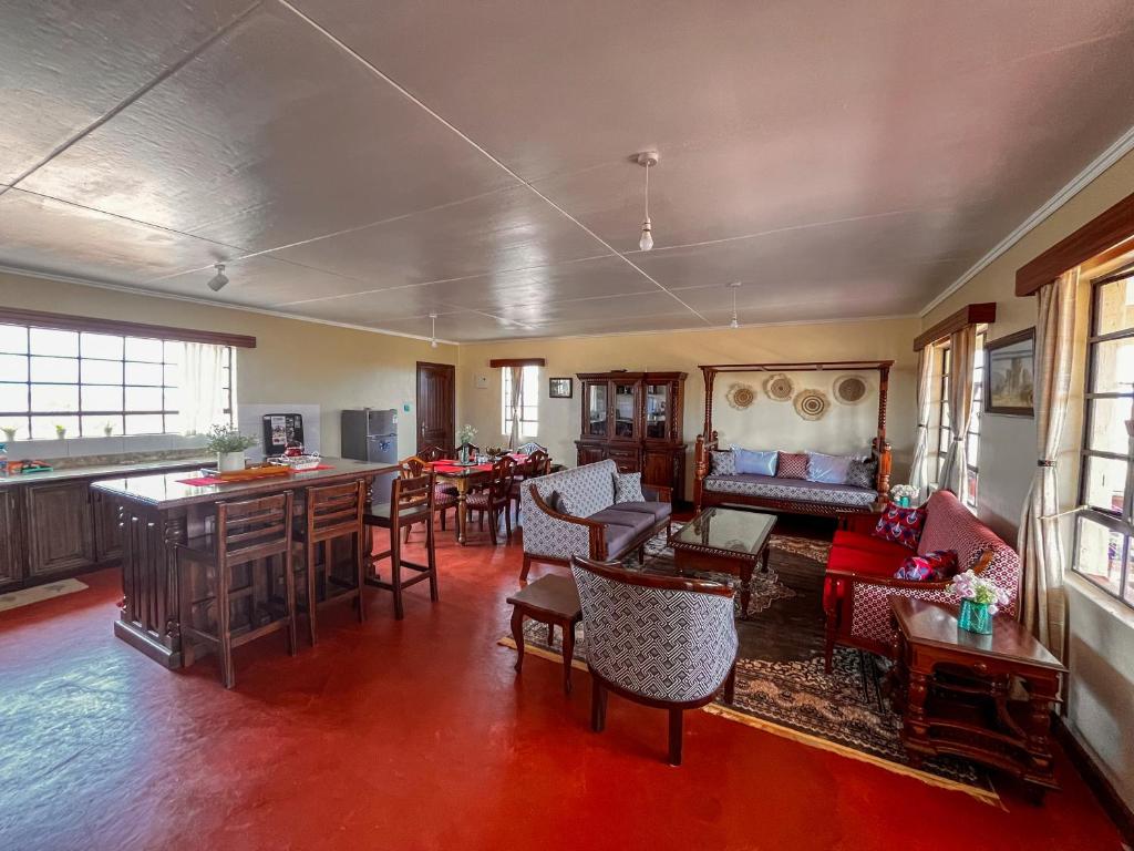 ein Wohnzimmer mit Tischen und Stühlen und eine Bar in der Unterkunft Wild Amboseli Ndovu Cottage. in Amboseli-Nationalpark