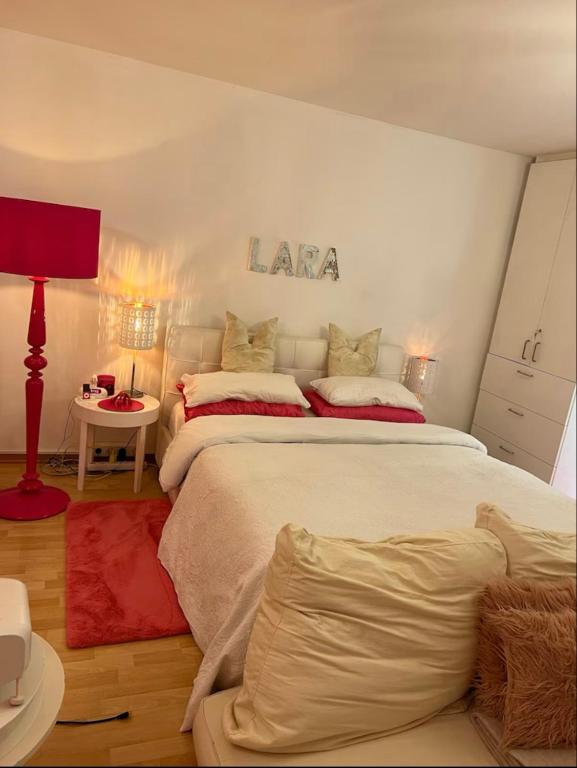 a white bedroom with a large bed and a red lamp at Charmante Suite im Untergeschoss in Düsseldorf