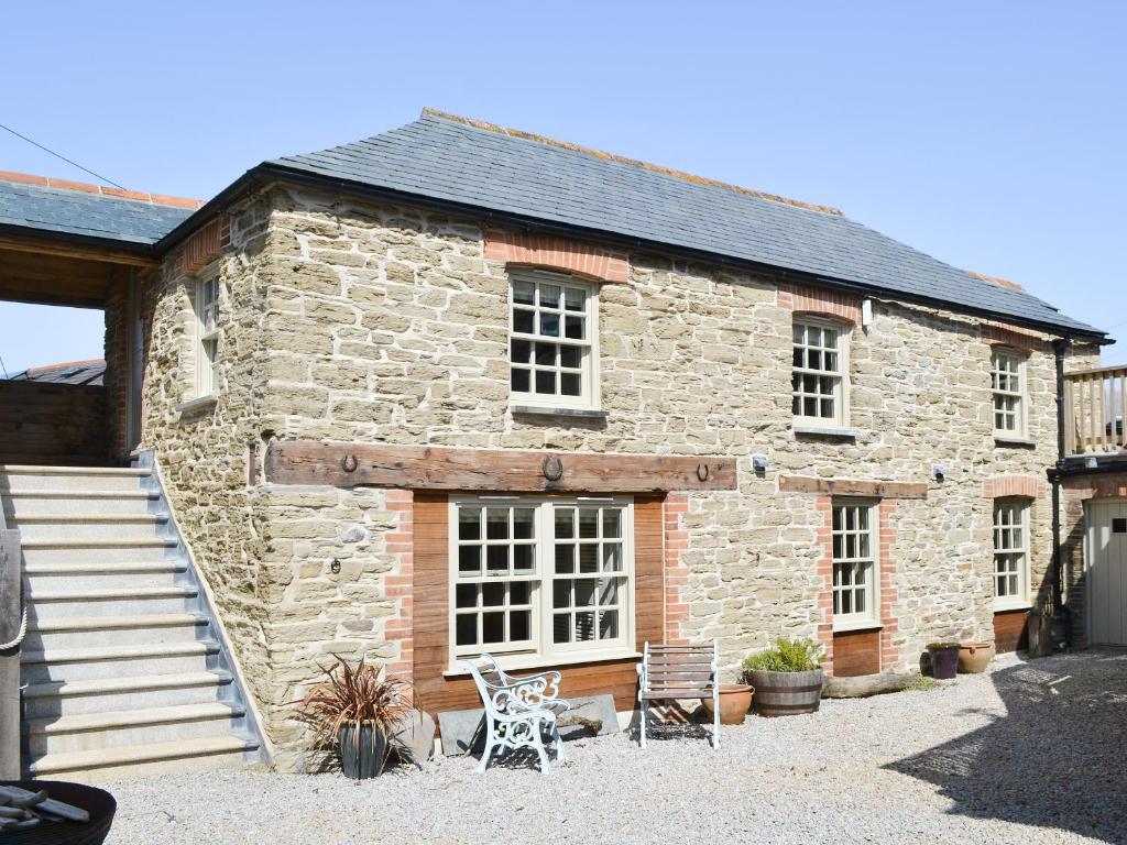 an old stone house with two chairs in front of it at The Stables By The Sea in Newquay