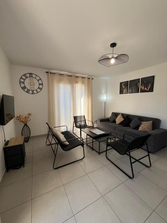 Una sala de estar con un sofá y sillas y un reloj. en Gîte neuf, à 12mn du Futuroscope, à la campagne-Le Coquelicot, en Saint-Léger