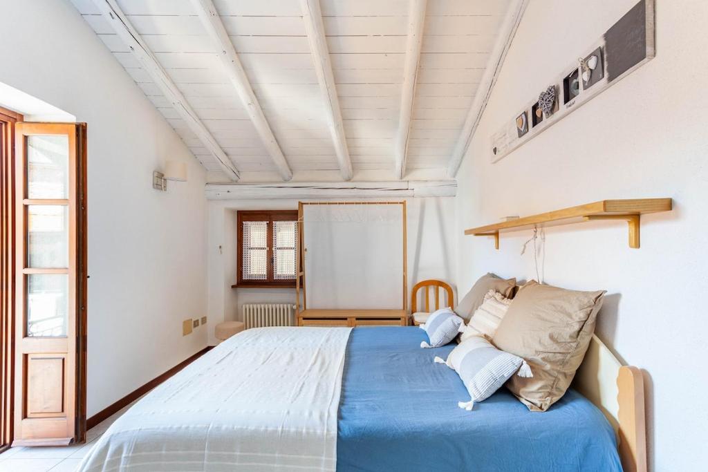 1 dormitorio con cama azul y techo blanco en Typical stone house with balcony, en Ossuccio