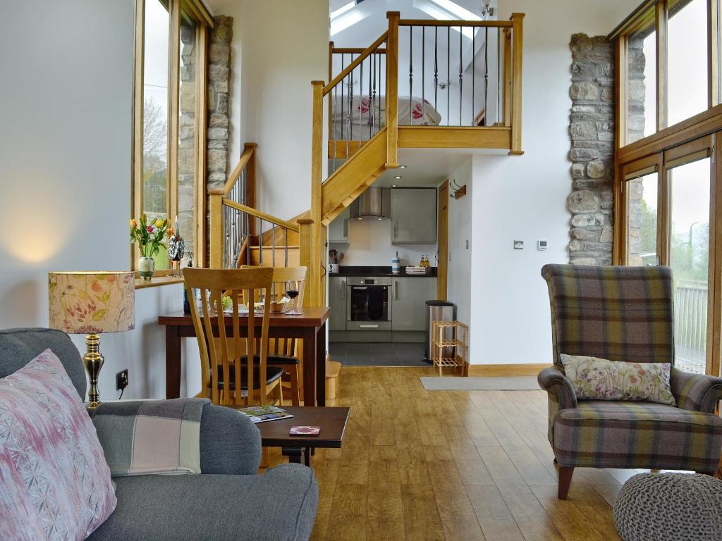 a living room with a couch and chairs and a staircase at Little Barn in Gilwern
