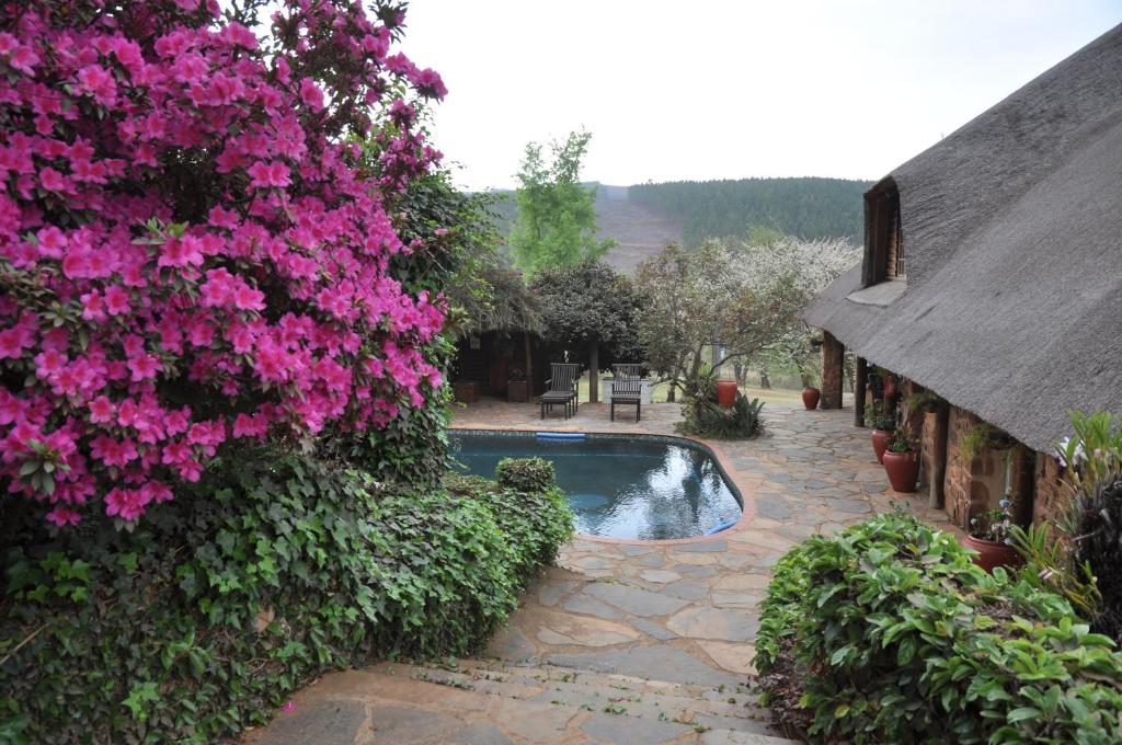 a swimming pool with pink flowers next to a house at Gunyatoo Trout Trout Farm & Guest Lodge in Sabie