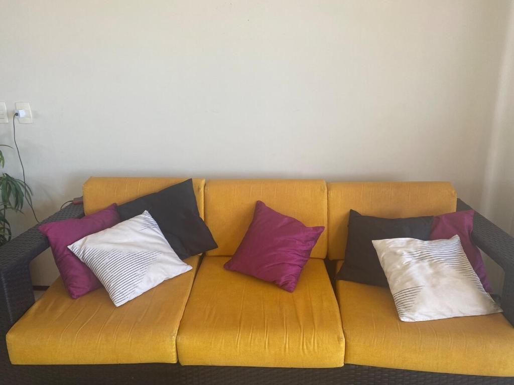 a yellow couch with four pillows on it at Porto das Dunas Apartment in Aquiraz