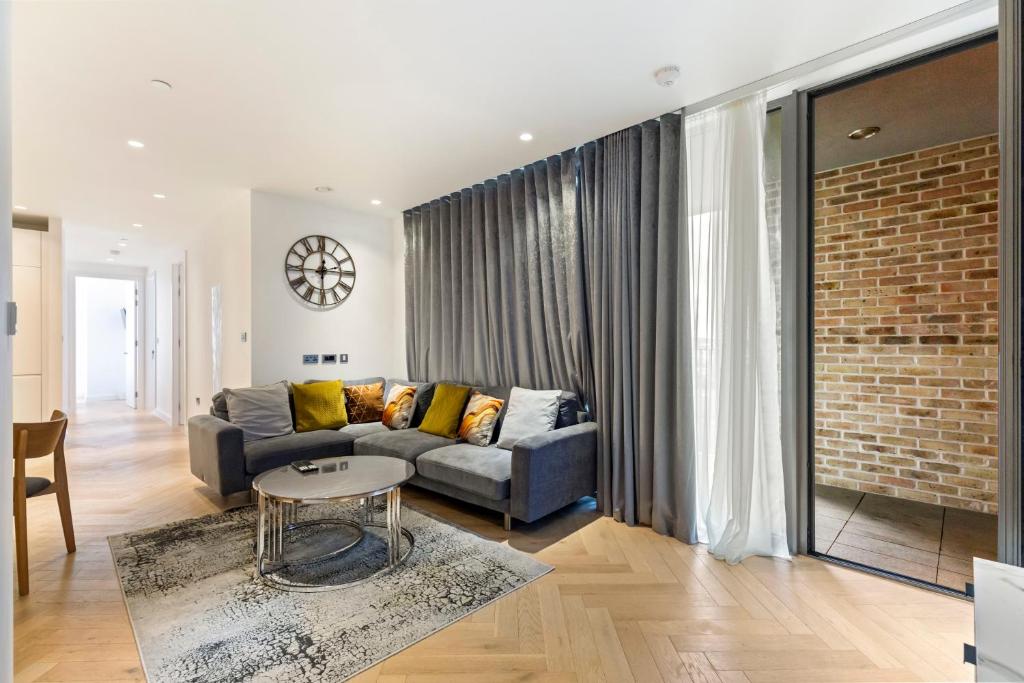 een woonkamer met een bank en een bakstenen muur bij Stylish Flat-Leisure Pool & Gym in Londen