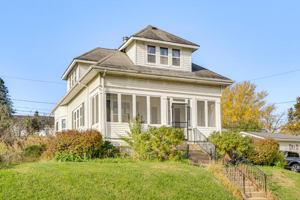 a white house with a porch on a lawn at 1 Mi to Downtown Dubuque! Spacious Home in Dubuque