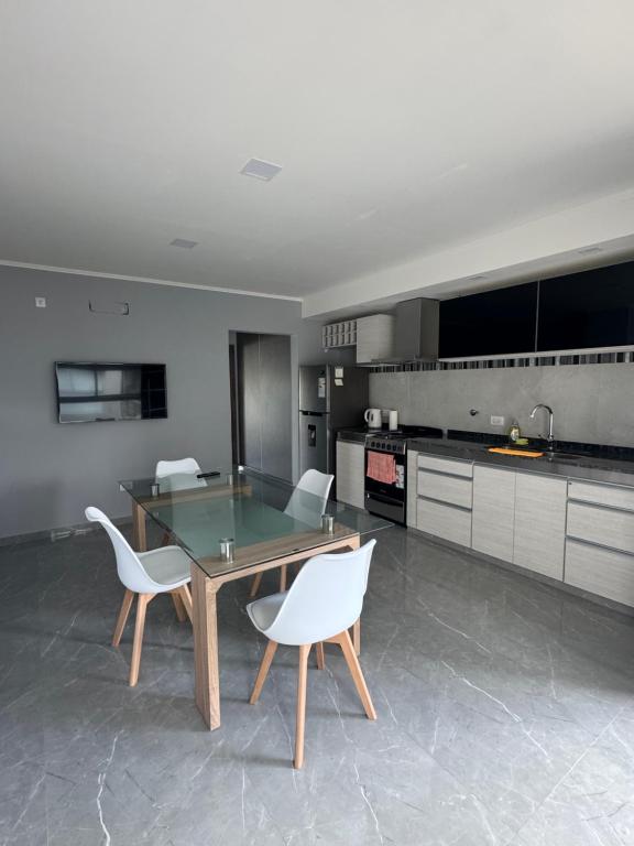 a kitchen with a glass table and white chairs at Alquileres temporales in Junín