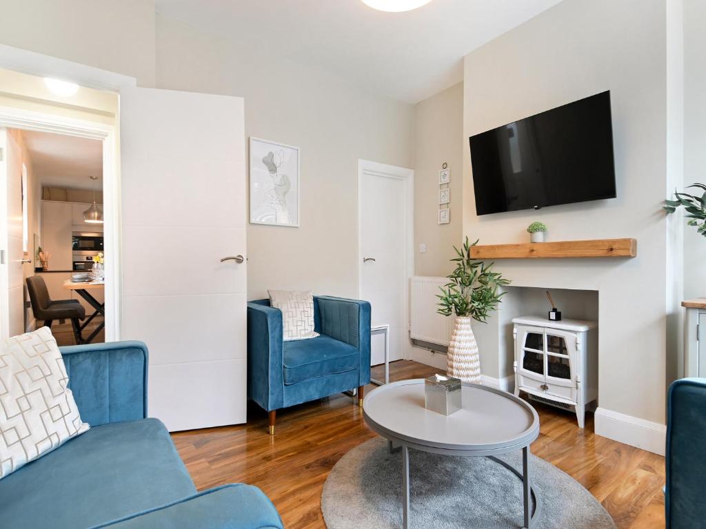a living room with blue chairs and a tv at Beaconsfield House in Mundesley