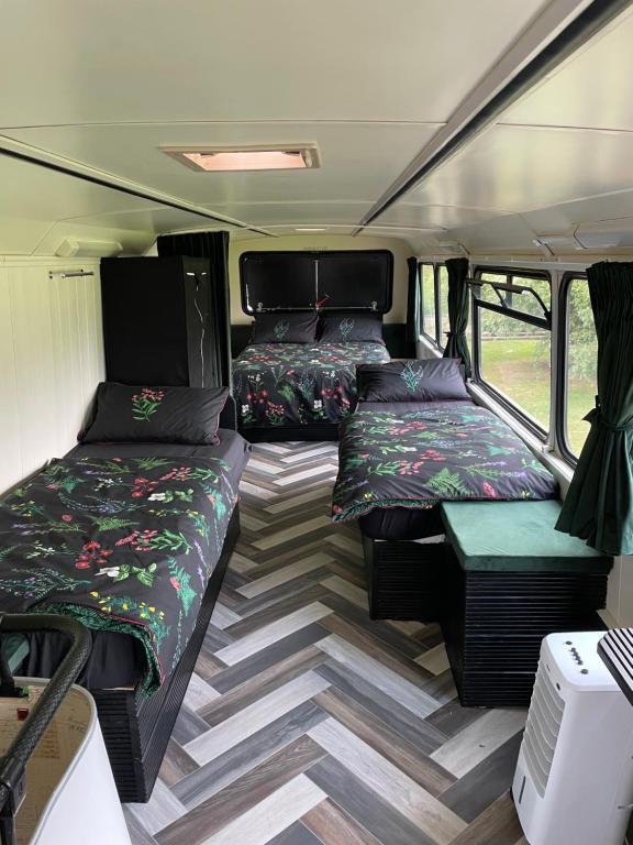 StickneyにあるWoodfarm Glampingのベッド2つとテーブル付きのキャンピングカー