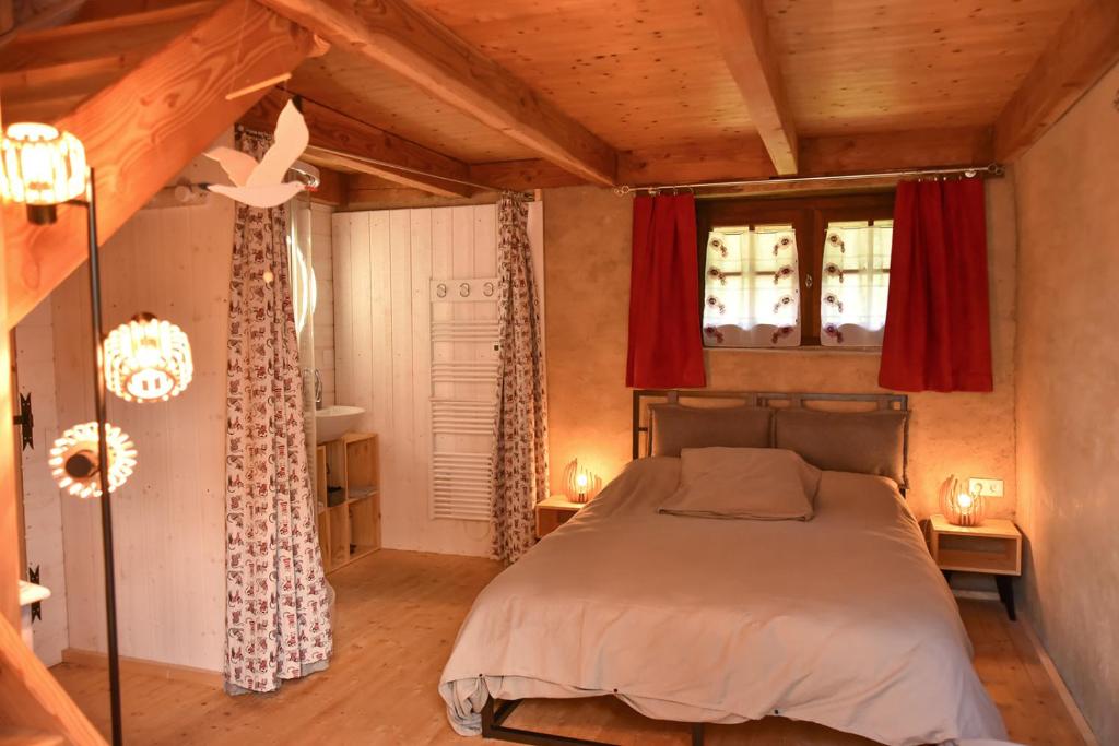 een slaapkamer met een bed in een kamer met houten plafonds bij Gîtes calmes écologiques in Saint-Symphorien