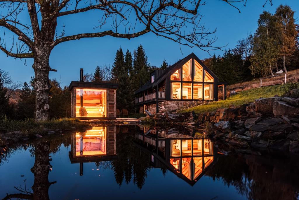 uma casa numa colina com um reflexo na água em Chata Pytlorka Beskydy offgrid wellness em Zahŭří