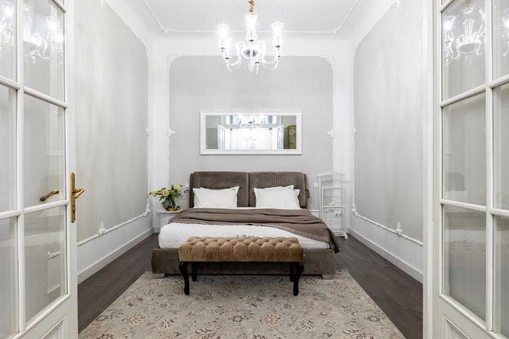 a white bedroom with a bed and a chandelier at Romari Братів Рогатинців 32 in Lviv