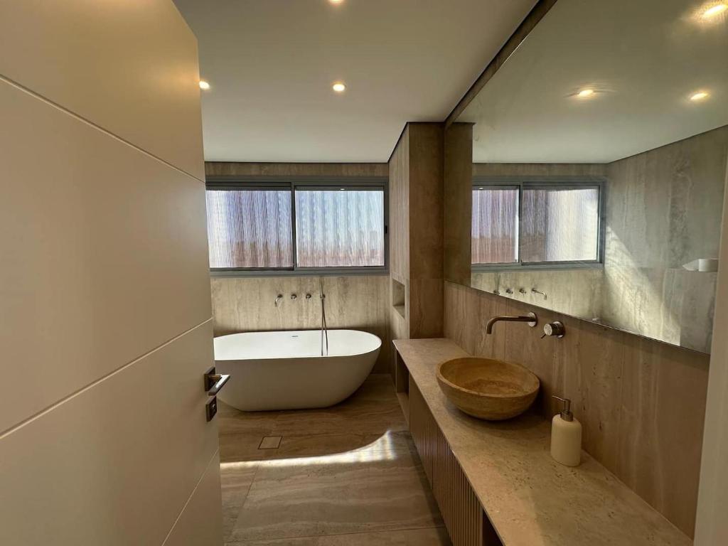 un bagno con una grande vasca e un lavandino di Tzafona Villa, Katzrin a Qatzrin